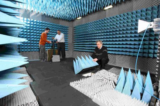 Engineers working inside the anechoic chamber, surrounded by blue RF-absorbing foam cones